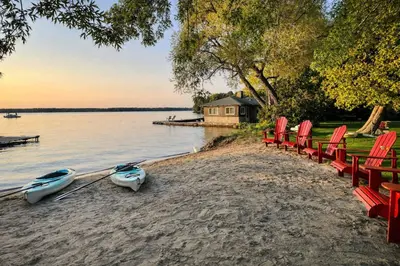 a group of red chairs and boats on a beach at Balsam Lake - 2-Bedroom Cottage #6 in Kawartha Lakes