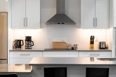 a kitchen with white cabinets and a stove top oven at RentX Cozy Downtown London Parking WiFi in London