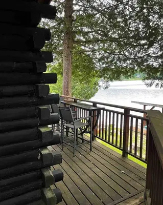 a wooden deck with chairs and a table and a tree at The Muskoka Nest in Utterson