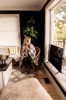 a woman sitting in a chair in a room with a window at The Muskoka Nest in Utterson