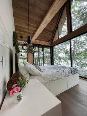 a bedroom with a bed in a room with windows at The Water’s Edge * * Unique Muskoka Treehouse * * in Utterson