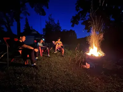a group of people sitting around a fire at night at Grand River Entire Cottage near Cambridge and Brantford in Cambridge