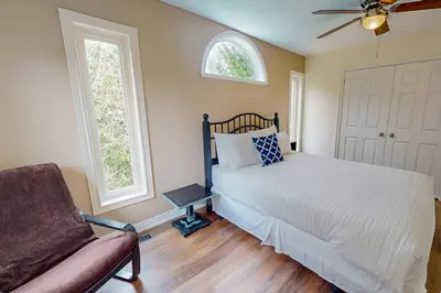 a bedroom with a bed and a chair and two windows at Monterra in Collingwood