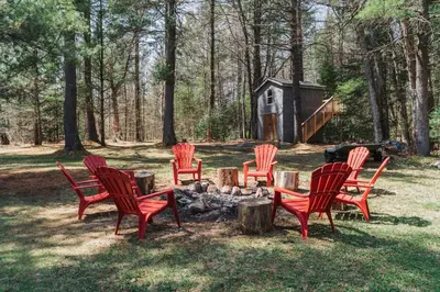 a group of red chairs sitting around a campfire at Private cottage with 26 acre & outdoor games in Bracebridge