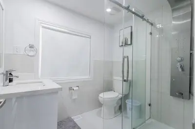 a white bathroom with a toilet and a shower at Private cottage with 26 acre & outdoor games in Bracebridge