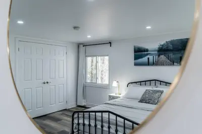 a bedroom with a bed and a mirror at Private cottage with 26 acre & outdoor games in Bracebridge