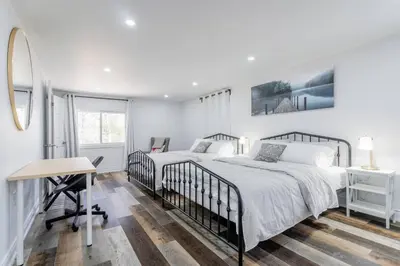 a white bedroom with two beds and a desk at Private cottage with 26 acre & outdoor games in Bracebridge
