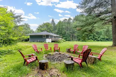 a group of red chairs sitting around a campfire at Private cottage with 26 acre & outdoor games in Bracebridge