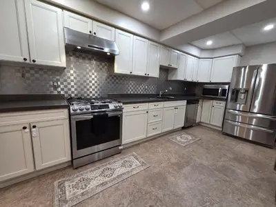 a kitchen with white cabinets and stainless steel appliances at Three Bedrooms House in Mississauga with free parking Conveniently located with easy access to the airport downtown Toronto major malls and highways for a seamless stay in Mississauga