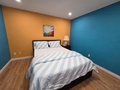 a bedroom with a bed with a blue and yellow wall at Three Bedrooms House in Mississauga with free parking Conveniently located with easy access to the airport downtown Toronto major malls and highways for a seamless stay in Mississauga