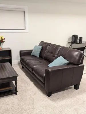 a brown leather couch in a living room at Spacious Luxury walk out Basement in Kitchener