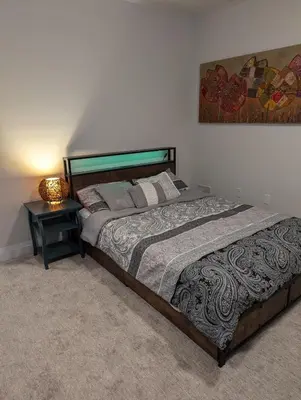 a bedroom with a large bed and a night stand at Spacious Luxury walk out Basement in Kitchener