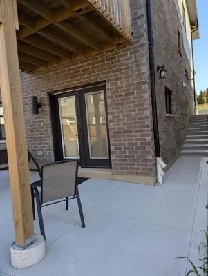 a chair sitting on a porch next to a brick building at Spacious Luxury walk out Basement in Kitchener