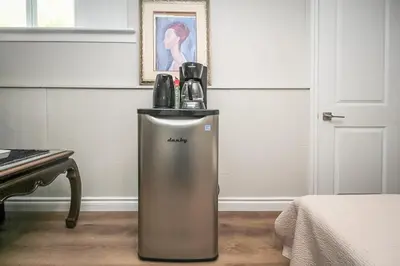 a silver refrigerator in a room next to a piano at The Beach House - Steps to Beach Area 3 4BR in Wasaga Beach