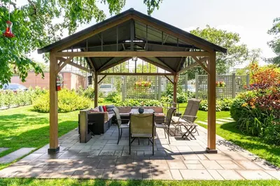 a pavilion with a table and chairs on a patio at Spacious Ground Floor Garden View Apartment in Wasaga Beach