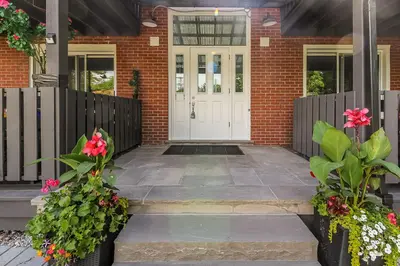 a brick house with a white door and flowers at Spacious Ground Floor Garden View Apartment in Wasaga Beach