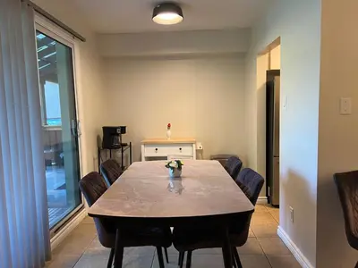 a dining room with a table and chairs at Spacious Ground Floor Garden View Apartment in Wasaga Beach