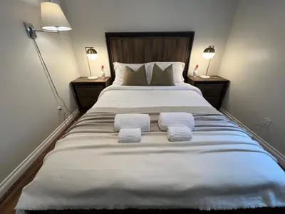 a bedroom with a large bed with two pillows at Spacious Ground Floor Garden View Apartment in Wasaga Beach