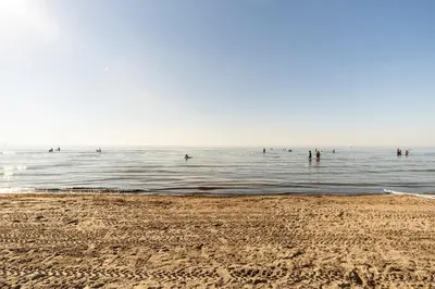a group of people in the water at the beach at Spacious Ground Floor Garden View Apartment in Wasaga Beach