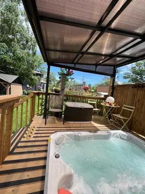 a hot tub on a deck with a roof at Spacious Second Floor Garden View Apartment in Wasaga Beach
