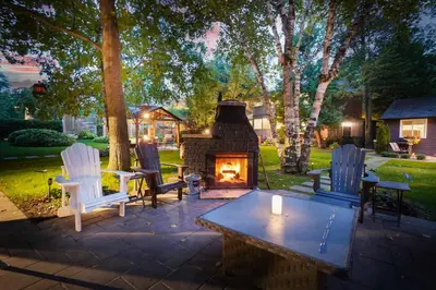 a patio with a fireplace and chairs and a table at Spacious Second Floor Garden View Apartment in Wasaga Beach