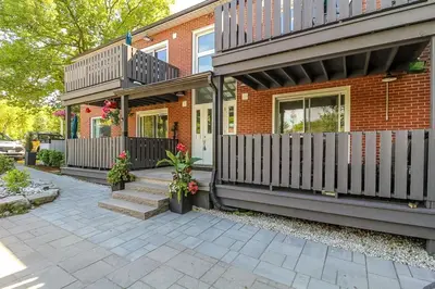 a brick house with a white picket fence at Spacious Second Floor Garden View Apartment in Wasaga Beach