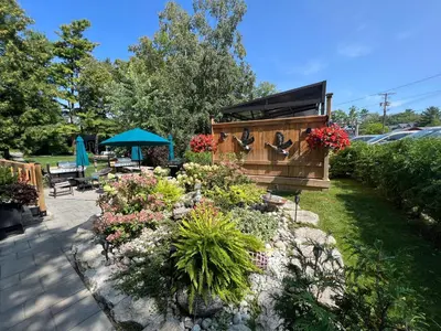 a backyard with a garden with flowers and a building at Spacious Second Floor Garden View Apartment in Wasaga Beach