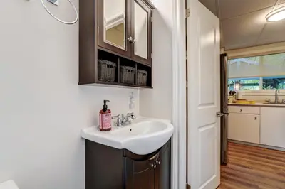 a bathroom with a white sink and a kitchen at The Cozy Shore Cottage - Large in Wasaga Beach