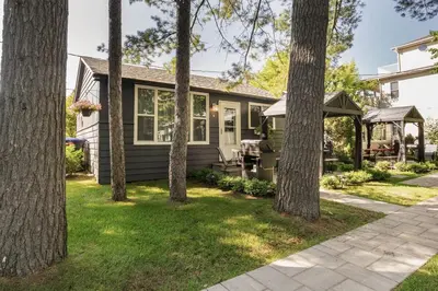 a house with trees in front of it at The Cozy Shore Cottage - Large in Wasaga Beach