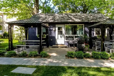 a small house with a porch and a patio at The Cozy Shore Cottage - Standard Attached in Wasaga Beach