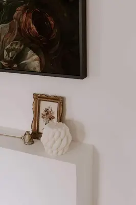 a white shelf with a picture and a vase on it at The Wild Rose - Cozy PEC Rental in Picton in Picton