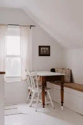a white room with a wooden table and a chair at The Wild Rose - Cozy PEC Rental in Picton in Picton