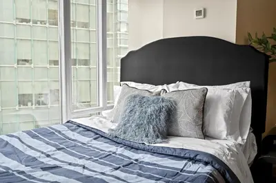 a bedroom with a bed with a black headboard and pillows at RivetStays - The Pantages Suite in Toronto