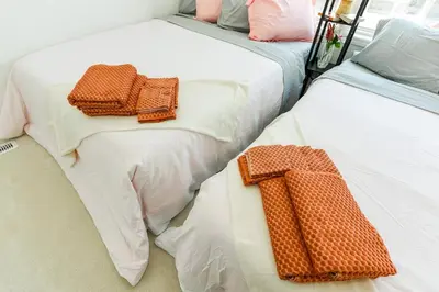 two beds with towels on them sitting next to each other at Brand New 7beds-kingbedsfamilysleep15playtable in Milton