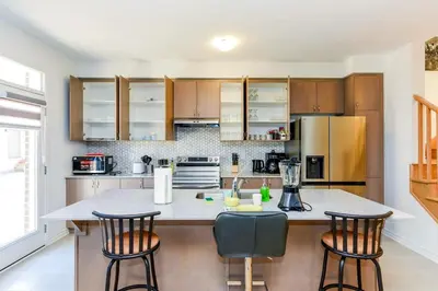 a kitchen with a large island with three bar stools at Brand New 7beds-kingbedsfamilysleep15playtable in Milton