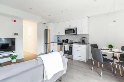 a living room with a couch and a kitchen at Westend Suites - Beautifully Furnished 3BR Apartment Close to High Park in Toronto