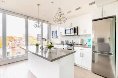 a kitchen with white cabinets and a large window at Westend Suites - Contemporary 3BR with Natural Light High Park North in Toronto