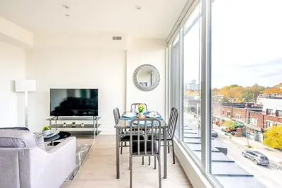 a dining room with a table and a large window at Westend Suites - Contemporary 3BR with Natural Light High Park North in Toronto