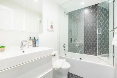 a white bathroom with a shower and a toilet at Westend Suites - Contemporary 3BR with Natural Light High Park North in Toronto