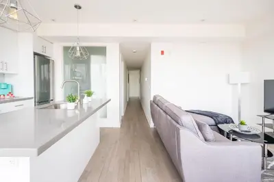 a kitchen and living room with a couch and a table at Westend Suites - Contemporary 3BR with Natural Light High Park North in Toronto