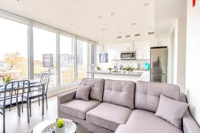 a living room with a couch and a kitchen at Westend Suites - Contemporary 3BR with Natural Light High Park North in Toronto