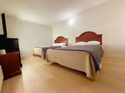 a bedroom with two beds and a flat screen tv at Idlewood Inn in Toronto