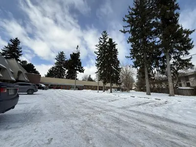 a snow covered parking lot with trees and a building at Idlewood Inn in Toronto