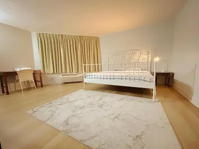 a bedroom with a white bed and a rug at Idlewood Inn in Toronto