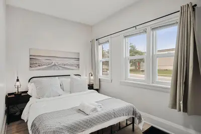 a white bedroom with a bed and two windows at Chic 2 BR Urban Retreat Near Beach Free Parking in Oshawa