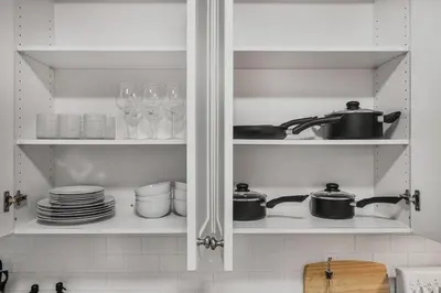 a kitchen cabinet filled with dishes and pots and pans at Chic 2 BR Urban Retreat Near Beach Free Parking in Oshawa