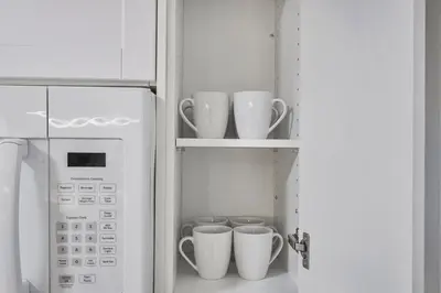 a refrigerator with cups on shelves next to a microwave at Chic 2 BR Urban Retreat Near Beach Free Parking in Oshawa