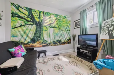 a living room with a large tree mural on the wall at Ora's Place BNB in Niagara Falls