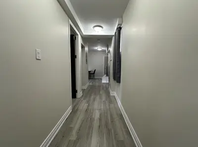 an empty hallway with white walls and wood floors at Furnished Simcoe Lofts in Oshawa