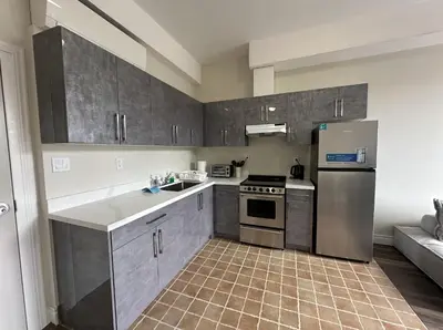 a kitchen with gray cabinets and a stainless steel refrigerator at Furnished Simcoe Lofts in Oshawa
